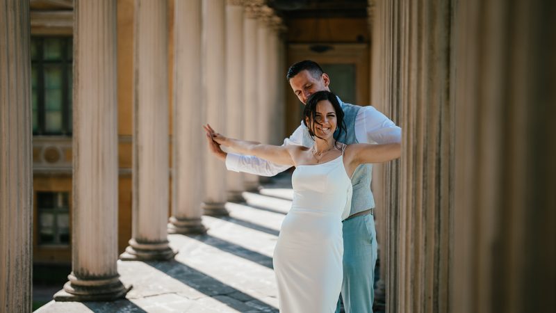 Bride and groom embracing among the columns of a grand colonnade, wedding photography by Moments by Tim